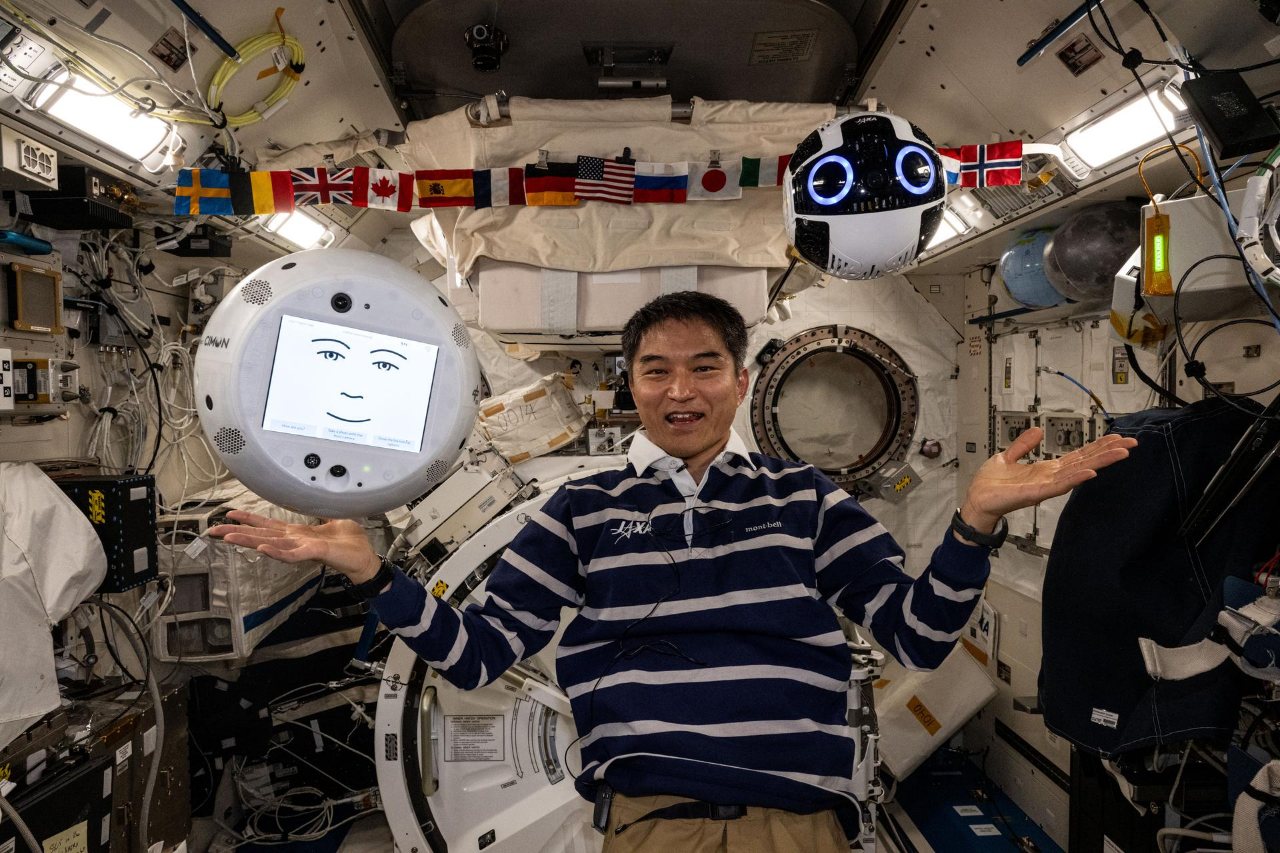 Kibo-তে JAXA-র নভোচারী কিমিয়া ইউই, সঙ্গে দুটো ভাসমান রোবট: CIMON, পর্দায় মুখের ছবিওয়ালা একটা সাদা বল, আর ওপরে ডানে Int-Ball2।